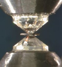 Vue de l'intérieur d'une cellule diamant. On observe les deux diamants taillés en pointe comprimant le joint, au centre duquel se trouve l'échantillon.
